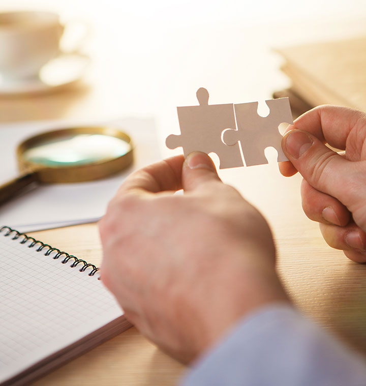 Hands fitting puzzle pieces together to represent joined-up MM2H advisory support